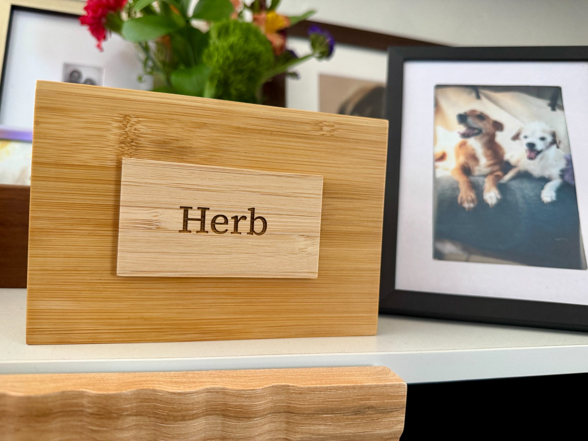 Herb's memorial urn with his name engraved, flowers and a framed photo nearby